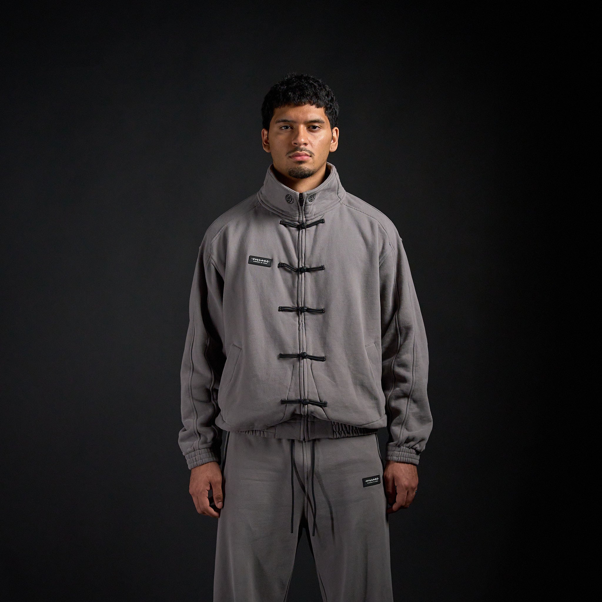 Tang Warmup Jacket in DARKSIDE charcoal grey, front view on model | Village Hidden in Iron