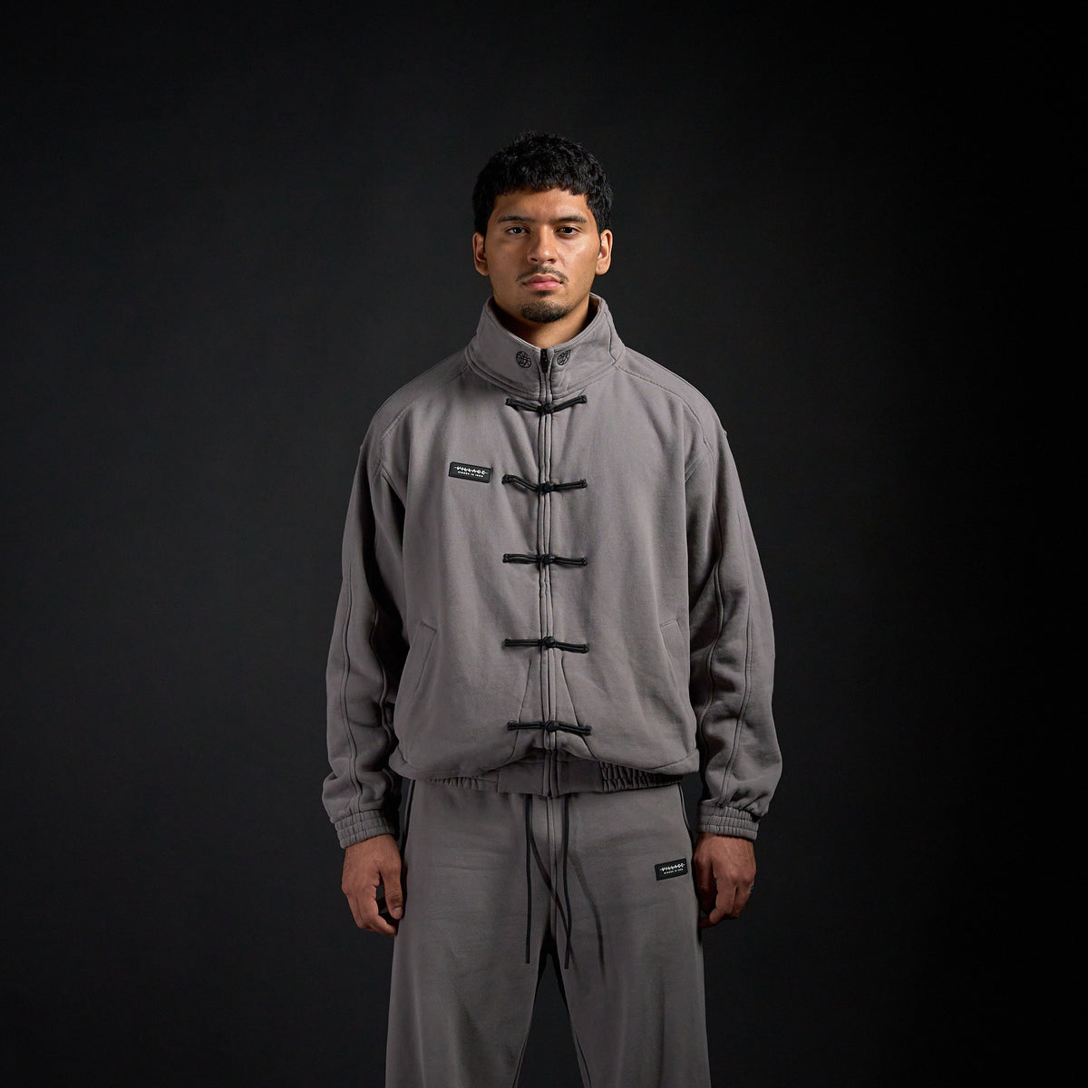 Tang Warmup Jacket in DARKSIDE charcoal grey, front view on model | Village Hidden in Iron
