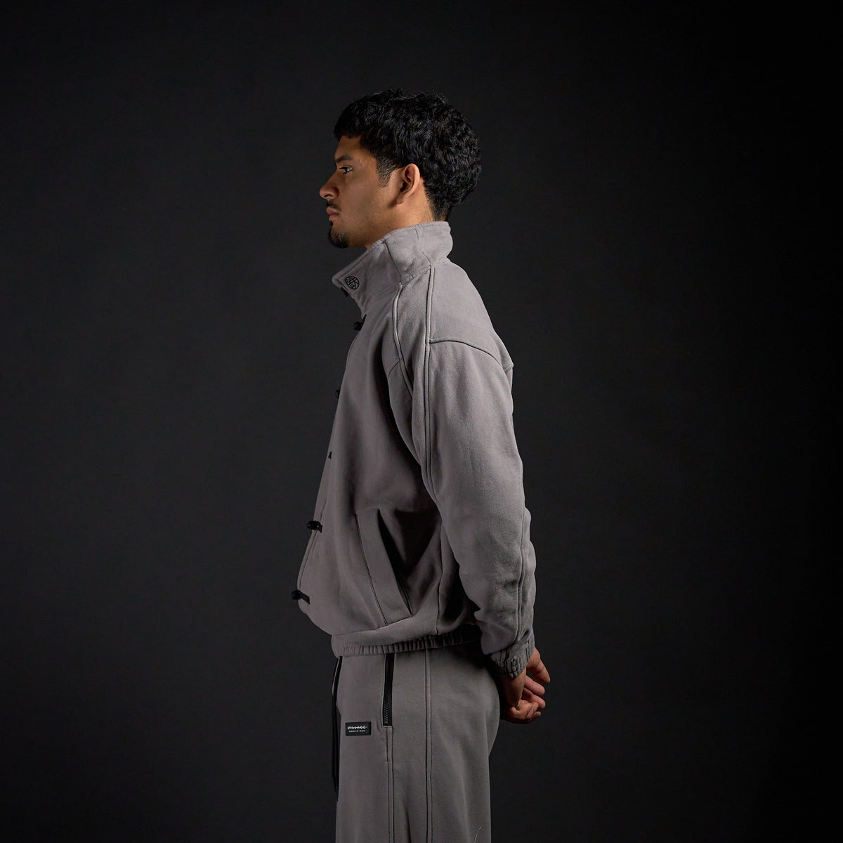Tang Warmup Jacket in DARKSIDE charcoal grey, side view on model | Village Hidden in Iron